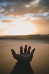 Picture of a hand reaching out to the sunset.